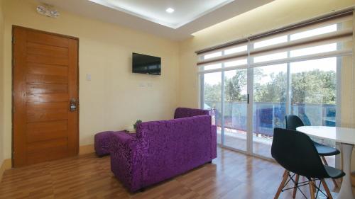 a living room with a purple couch and a table at RedDoorz at Casa Barcelona Condotel in Iloilo City