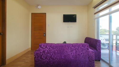 a purple couch in a living room with a tv at RedDoorz at Casa Barcelona Condotel in Iloilo City