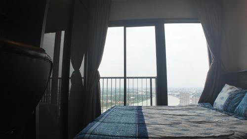 a bedroom with a bed and a large window at Luxury Riverside Private Condo Bangkok North Area in Ban Sai Ma