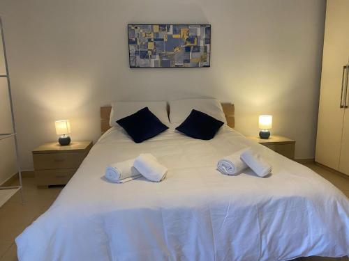una camera con un letto bianco con due cuscini di St Julians Central Apartment a San Giuliano