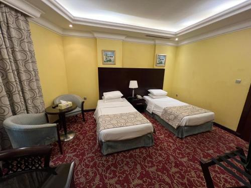 a hotel room with two beds and a chair at Musherib Hotel in Doha