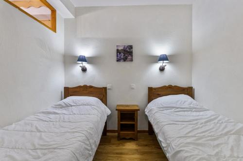 - 2 lits dans une chambre avec 2 lampes sur le mur dans l'établissement Résidence Les Hauts De Preclaux - Appartement exposé sud au coeur des Orres 1800 MAE-1651, aux Orres