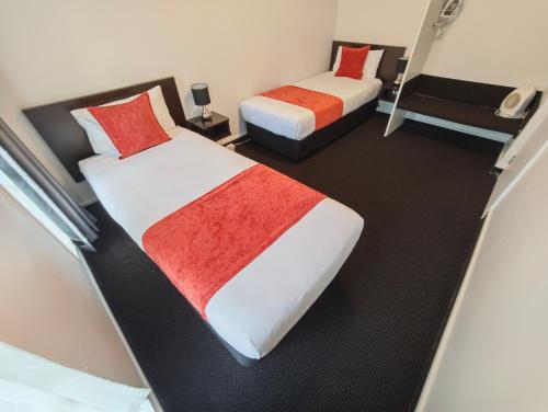 two beds in a hotel room with red and white blankets at Great Lake Motel Taupo in Taupo
