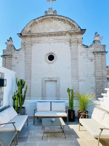 an old brick building with white furniture and plants at Palazzo Mulini in Monopoli