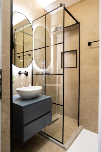 a bathroom with a sink and a glass shower at AL Apartments Tirana in Tirana