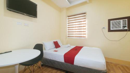 a bedroom with a bed and a table and a television at RedDoorz at Casa Barcelona Condotel in Iloilo City