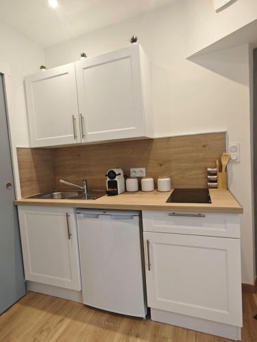une cuisine avec des armoires blanches et un évier dans l'établissement Le cocon de la chouette, à Dijon
