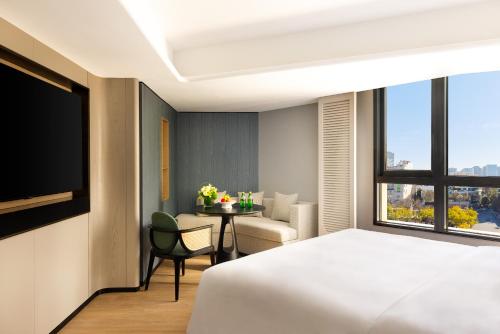 a bedroom with a bed and a table with a chair at 昆明开臣Kasion酒店 in Kunming