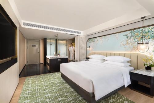 a bedroom with a large white bed and a bathroom at 昆明开臣Kasion酒店 in Kunming