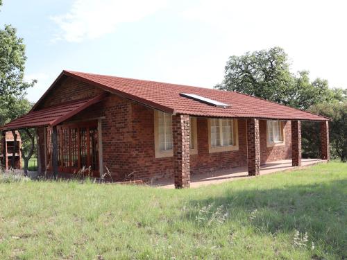 a small brick house with a red roof at Guesthouse in the Waterberg in Ouklip