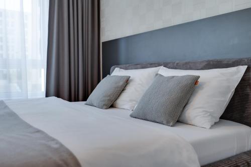 a bed with white sheets and pillows in a room at Apartmán Galileo in Trnava