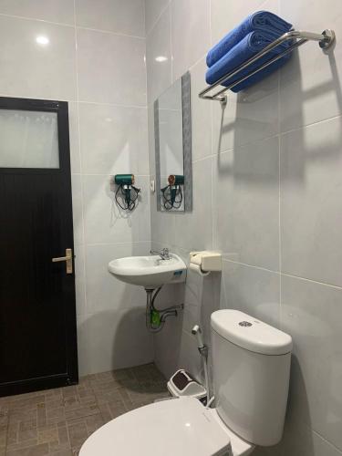a white bathroom with a toilet and a sink at Gubuk Ndeso Bromo in Bromo