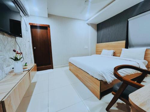 a bedroom with a bed and a chair and a tv at Harvey's Hotels - Gowlidoddy - Near US Consulate in Hyderabad