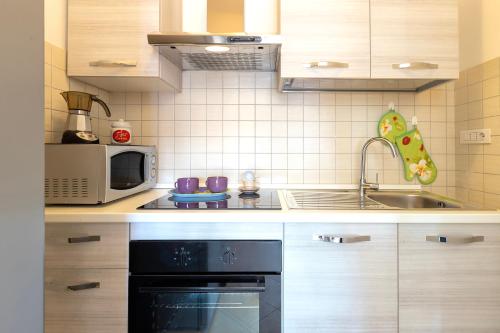 a kitchen with a sink and a stove and a microwave at Charlie Beach in Castelsardo