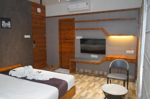 a hotel room with a bed and a tv at Abssolute Homtel - Rooms & Suites in Pune