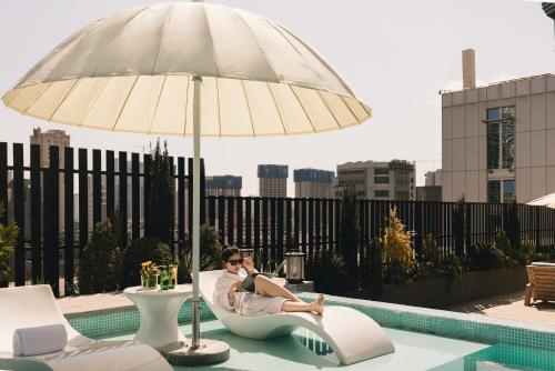 a woman sitting in a chair under an umbrella next to a pool at 昆明开臣Kasion酒店 in Kunming