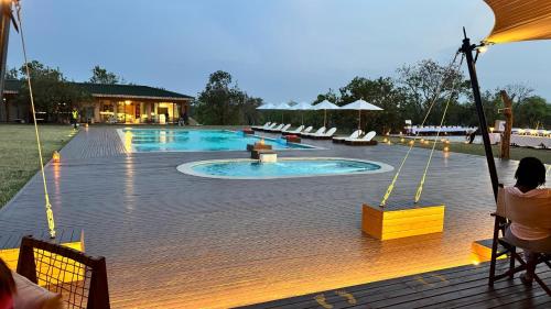a swimming pool with a deck and chairs and a building at Entikko Safari Lodge in Fajao