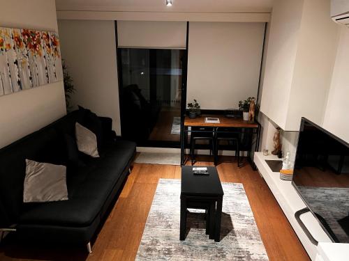a living room with a black couch and a table at Urban Eden in South Yarra in Melbourne