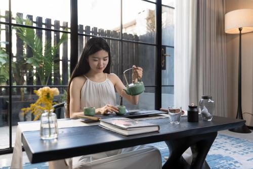 a woman sitting at a table drinking from a green cup at 昆明开臣Kasion酒店 in Kunming