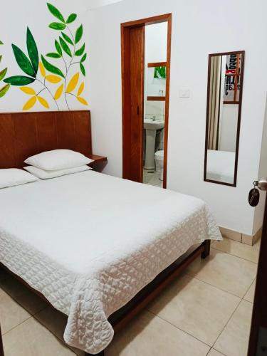 a bedroom with a white bed and a mirror at Piccolo Bed & Breakfast in Tarapoto