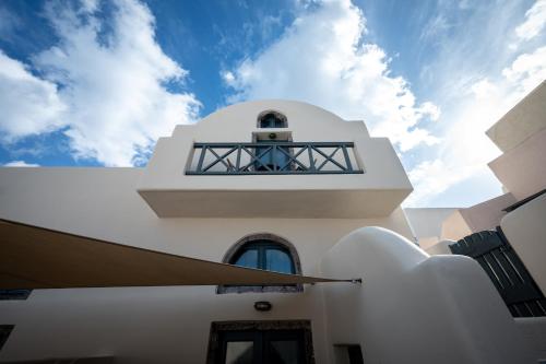 a white building with a balcony on top of it at Lotza Studios in Oia