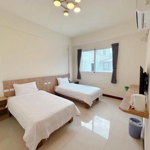 a hotel room with two beds and a television at Blue Sky Hill Chishangkan B&B in Chishang