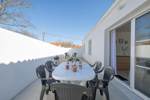 une table blanche et des chaises sur une terrasse dans l'établissement Maison Corail 3 - Parking privé proche plage, à Saint-Pierre-dʼOléron