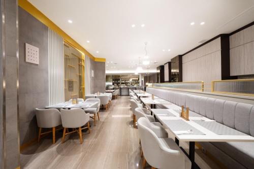 a restaurant with white tables and white chairs at Erian Hotel in Jakarta