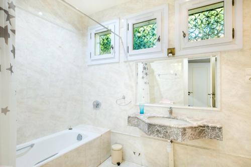 La salle de bains est pourvue d'une baignoire, d'un lavabo et de fenêtres. dans l'établissement Villa Eden, à Menton