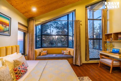 a bedroom with a large window with a couch and a desk at StayVista at Villa Vienna with Lawn & Bonfire in Mukteswar