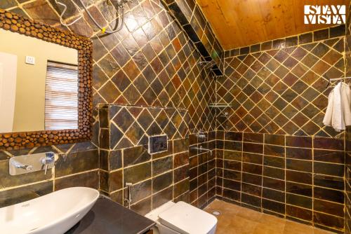 a bathroom with a sink and a toilet and a mirror at StayVista at Villa Vienna with Lawn & Bonfire in Mukteswar