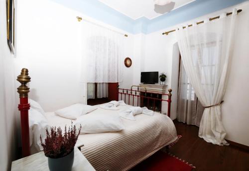 a bedroom with a bed with white sheets and a tv at Palladio Hotel - Portaria in Portaria