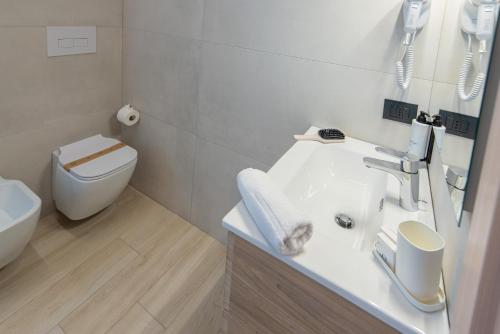 a white bathroom with a sink and a toilet at Ile Hotel in Peschiera del Garda