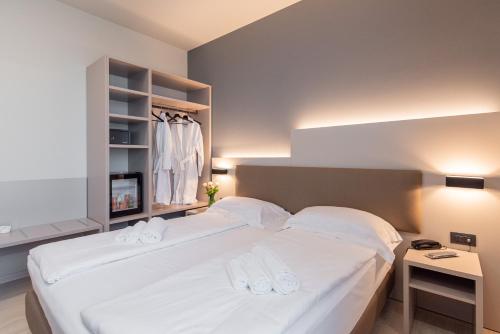 a bedroom with a bed with white sheets and towels at Ile Hotel in Peschiera del Garda