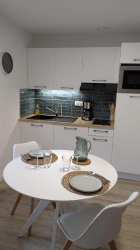 Una cocina blanca con una mesa y sillas blancas. en Studio centre thermal touristique - Casa Amnéville, en Amnéville