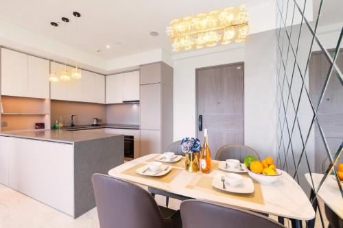a kitchen with a wooden table and chairs and a kitchen with white cabinets at THE METROPOLE Apartment Complex OPERA-GALLERIA-CREST in Ho Chi Minh City
