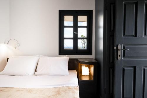 a bedroom with a bed with white sheets and a window at Lotza Studios in Oia