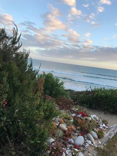a beach with a pile of rocks and the ocean at Africa Unwined Beach house in Witsand