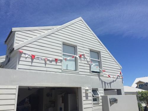 a white house with red and white flags on it at Africa Unwined Beach house in Witsand