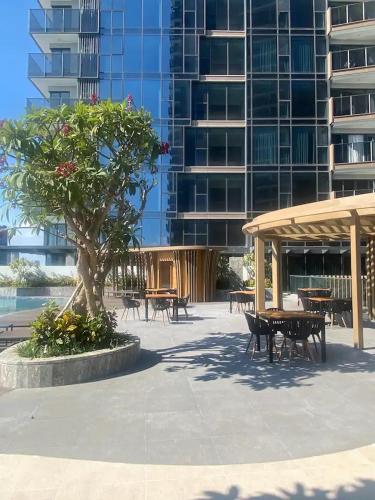 a tree in a courtyard with tables and a building at THE METROPOLE Apartment Complex OPERA-GALLERIA-CREST in Ho Chi Minh City