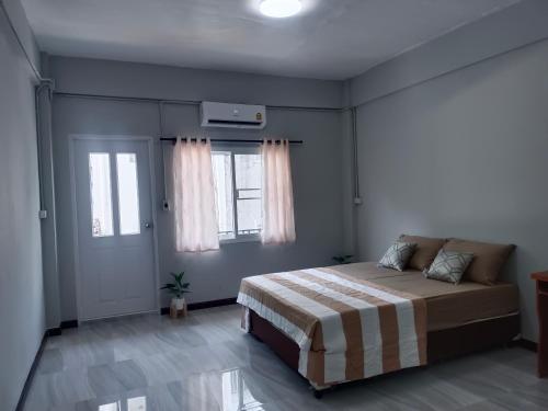 a bedroom with a bed and two windows at The little home in Bangkok