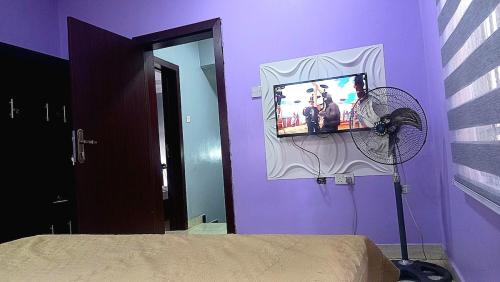 a bedroom with a purple wall with a tv and a fan at Budget Friendly 2bedDuplex , 15 mins to the Airport in Lagos