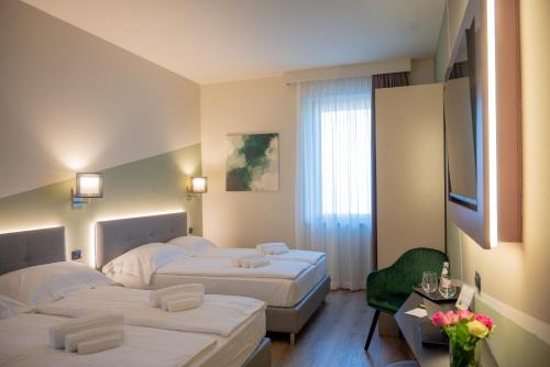 a hotel room with two beds and a flat screen tv at Ile Hotel in Peschiera del Garda