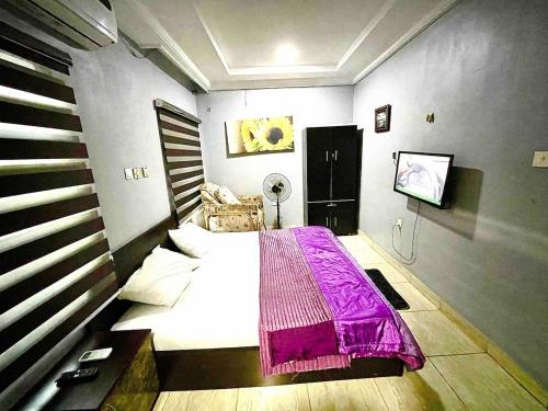 a bedroom with a bed with a purple blanket at Budget Friendly 2bedDuplex , 15 mins to the Airport in Lagos