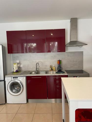 - une cuisine avec des placards rouges et un lave-linge dans l'établissement EVASION AU FIL DE L EAU une pause avec jardin au bord du Canal du Midi, à Castelnaudary
