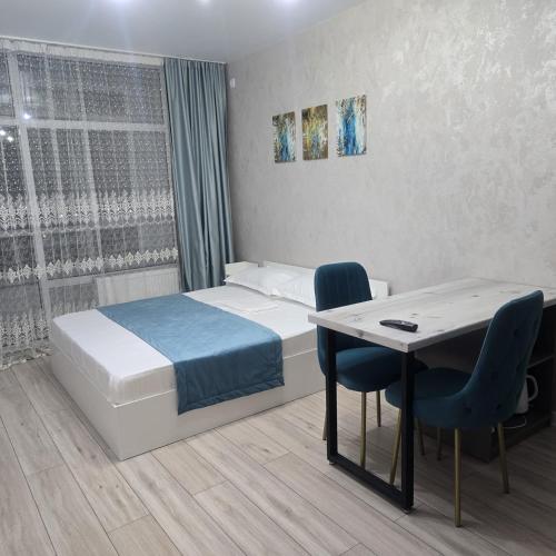 ein Schlafzimmer mit einem Bett und einem Tisch und Stühlen in der Unterkunft ЖК Панорама Парк in Qostanai