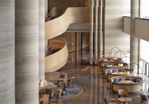 a lobby with tables and chairs and a staircase at Beihai Marriott Resort in Beihai