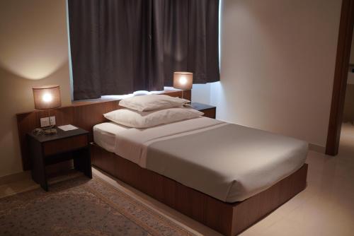 a bedroom with a large bed with two night stands at Nassim Al Najaf Hotel in An Najaf