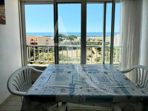 - une table en face d'une fenêtre avec vue sur la plage dans l'établissement Studio cabine avec parking, face a la mer, à Sète