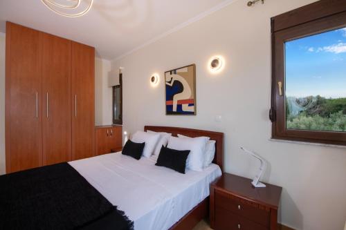a bedroom with a bed with white sheets and a window at Villa Althaea in Loutra